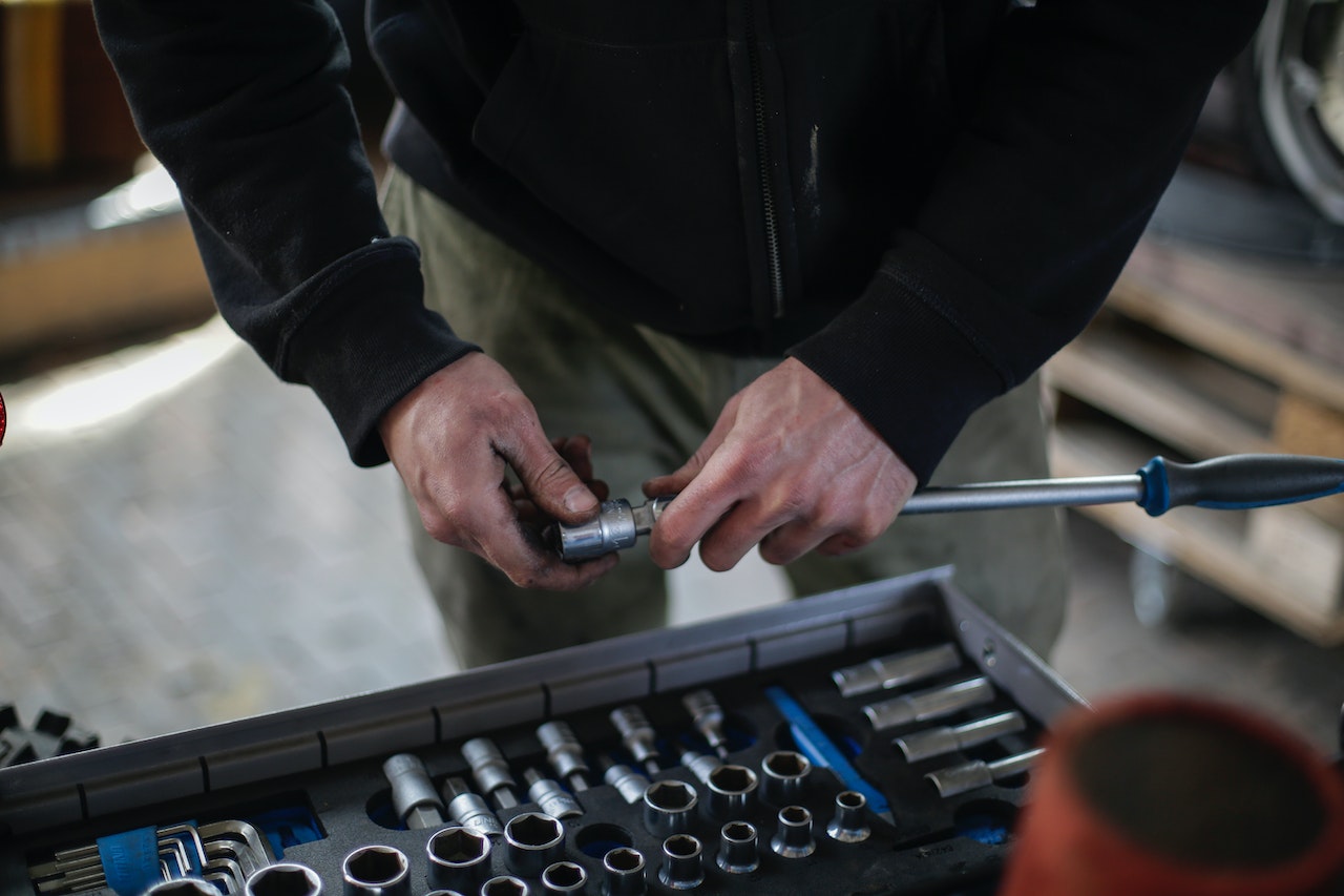Faceless male mechanic in workshop taking metal socket from toolbox 